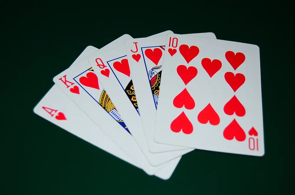 Royal flush in hearts laid out on green felt, a question of whether CS2 gambling is legal