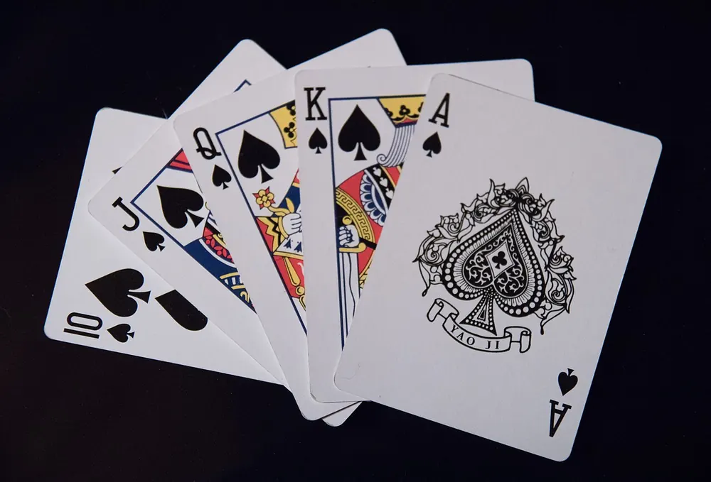 Hand of playing cards with a royal flush in spades