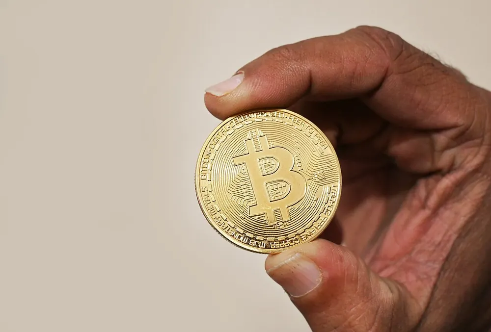 Hand holding a gold bitcoin coin