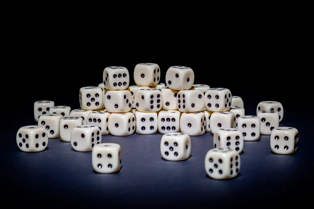 Many white dice spread across a dark surface