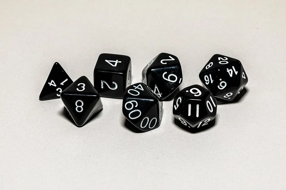 Black polyhedral dice on a white background, rolling for the best CS2 case to open