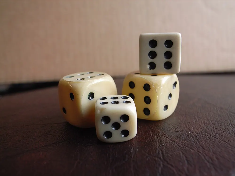 Cream colored dice stacked on a wooden table, before a Clash.gg deposit