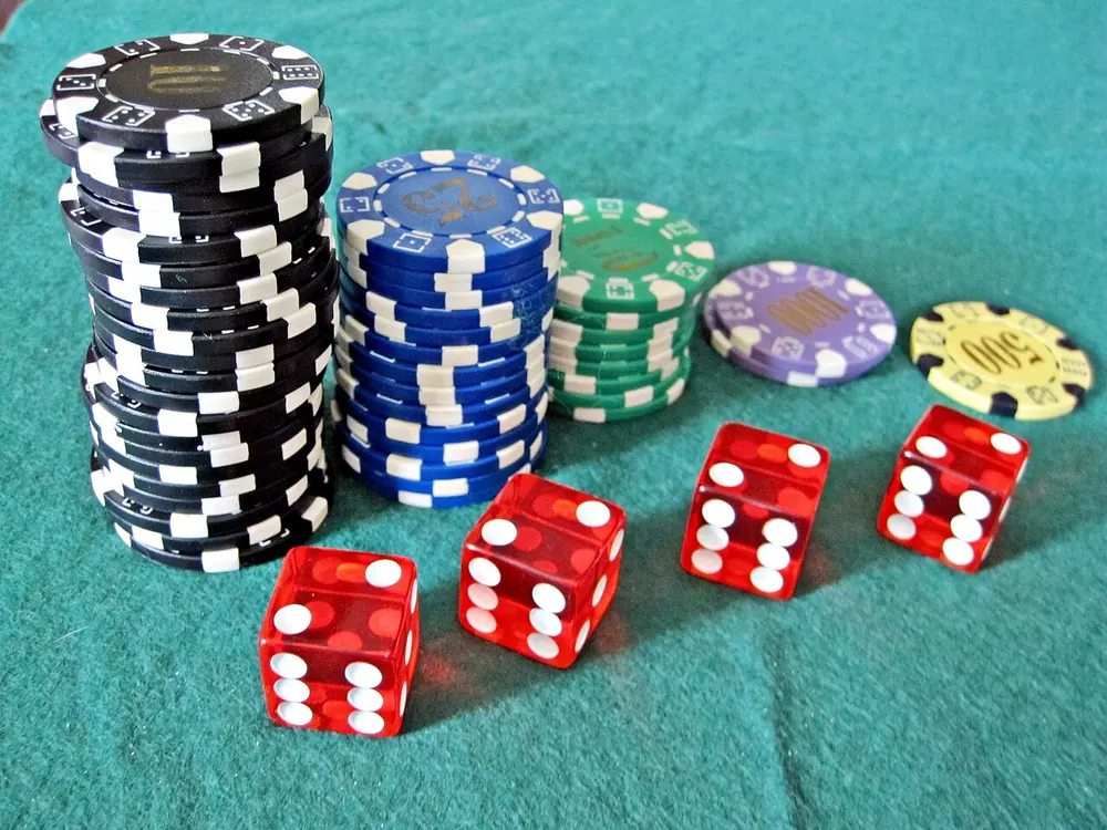 Poker chips and red dice on a teal felt table