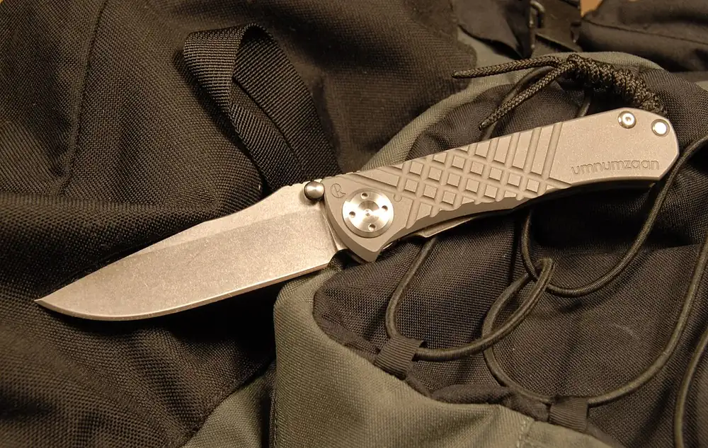 Folding knife with a textured handle on a dark cloth, the kind of knife people sell CS2 skins for