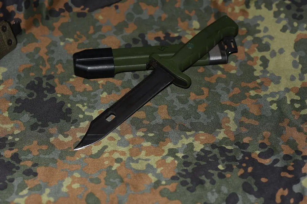 Combat knife lying on camouflage fabric