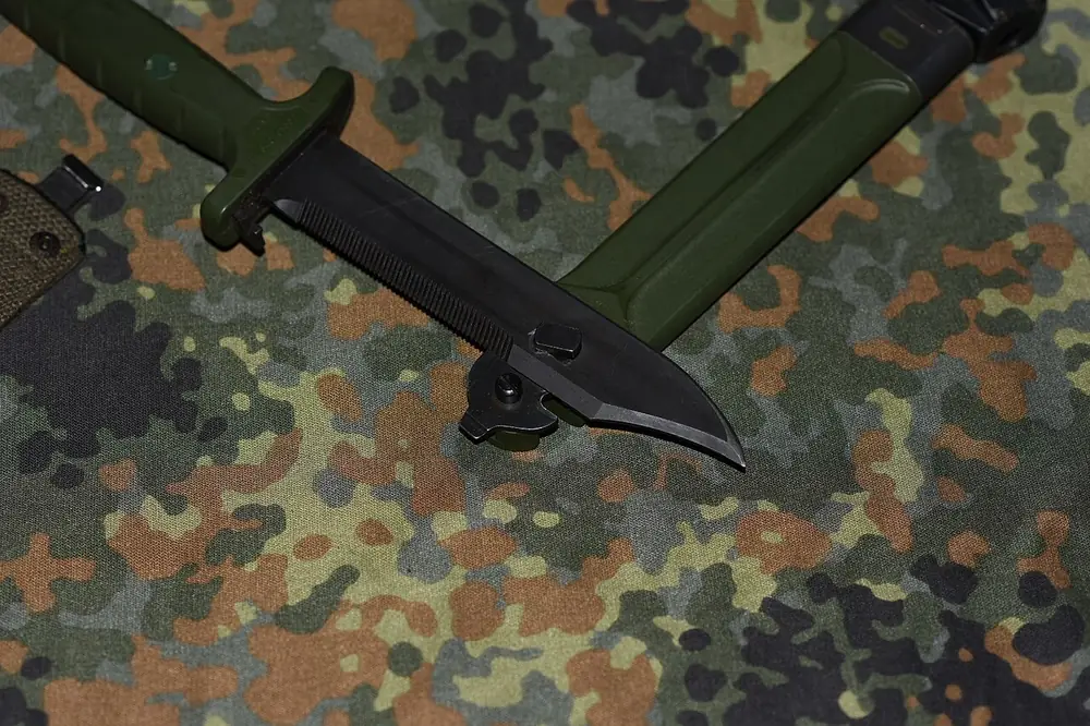 Combat knife with a wire cutter on camouflage fabric