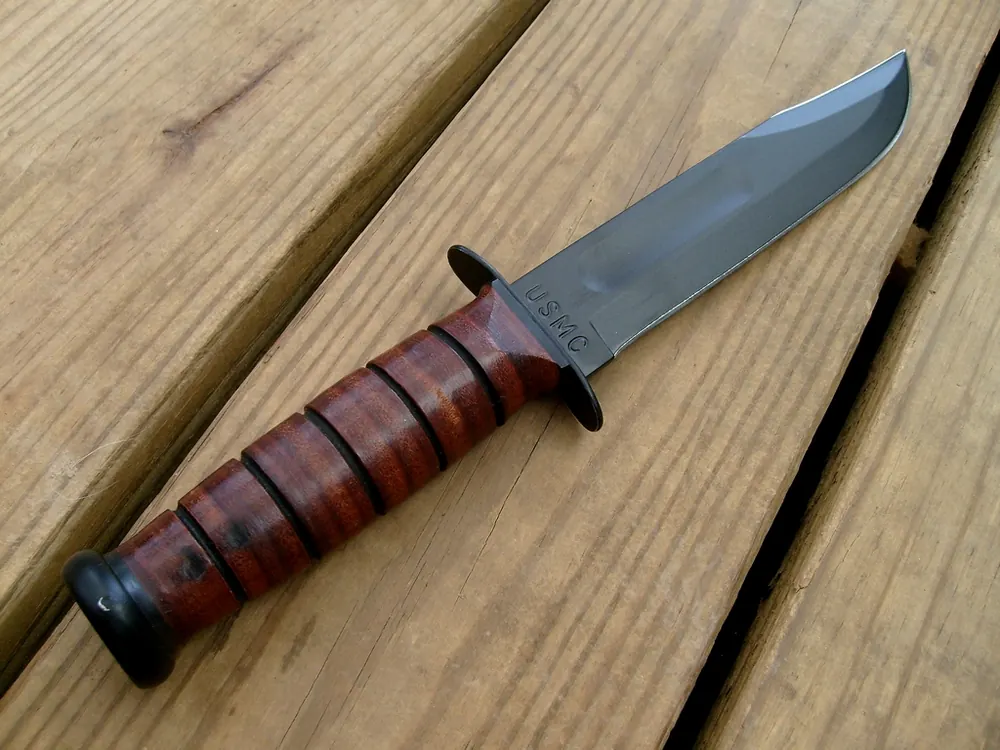 Combat knife with a leather handle on wooden planks, a Gamma Doppler knife hunt