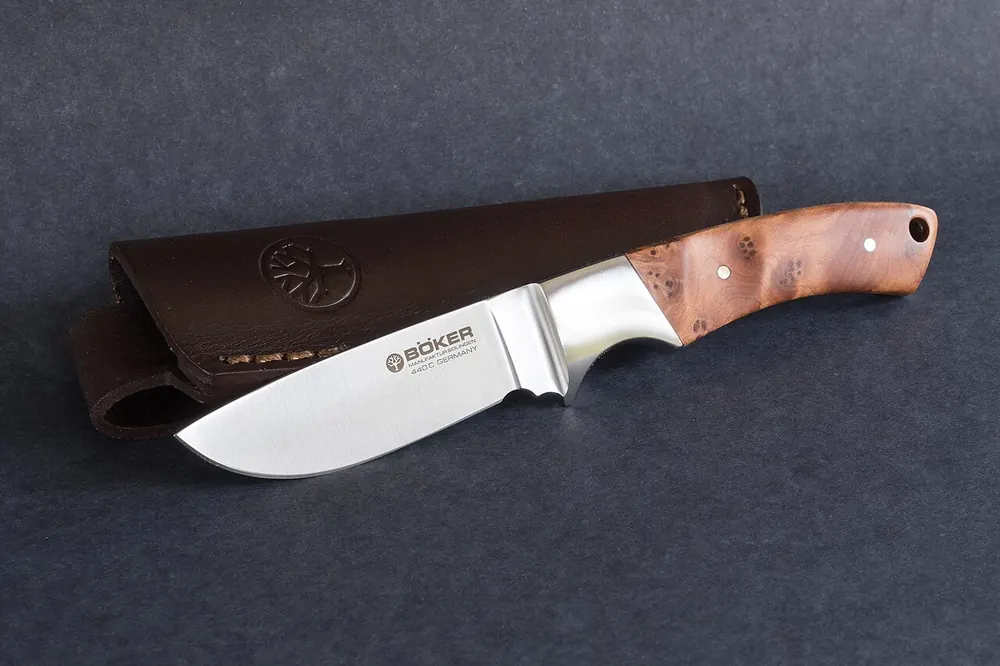 Hunting knife with a wooden handle and leather sheath, ranking CS2 gloves and knives