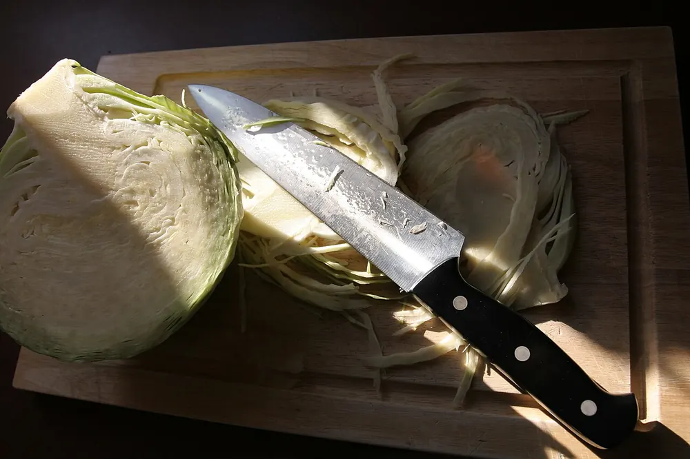 Steel kitchen knife next to sliced cabbage