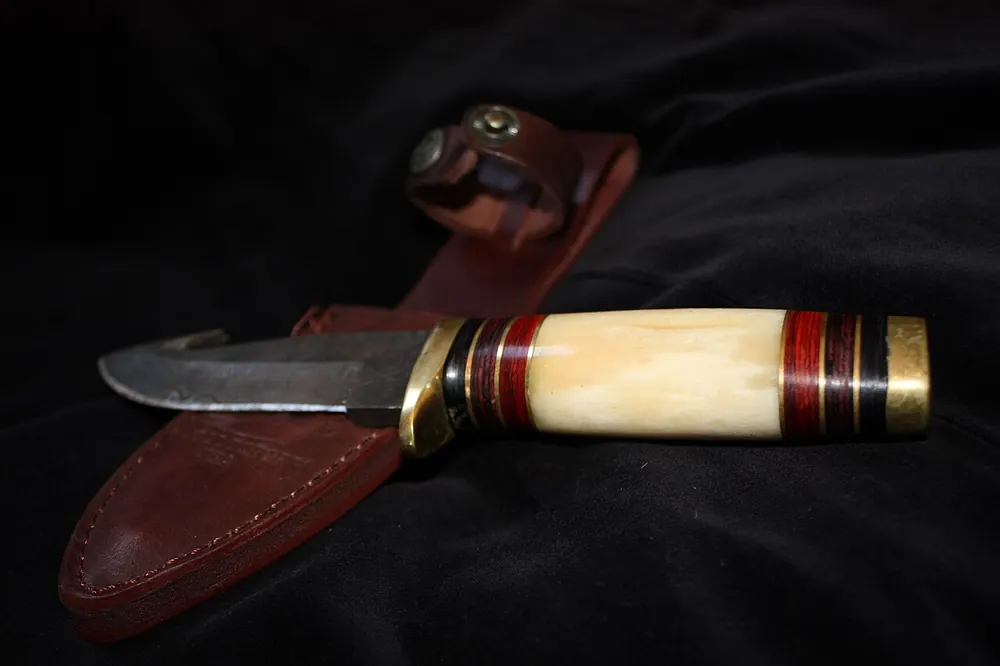 Hunting knife with a bone handle and leather sheath, condition that float value measures