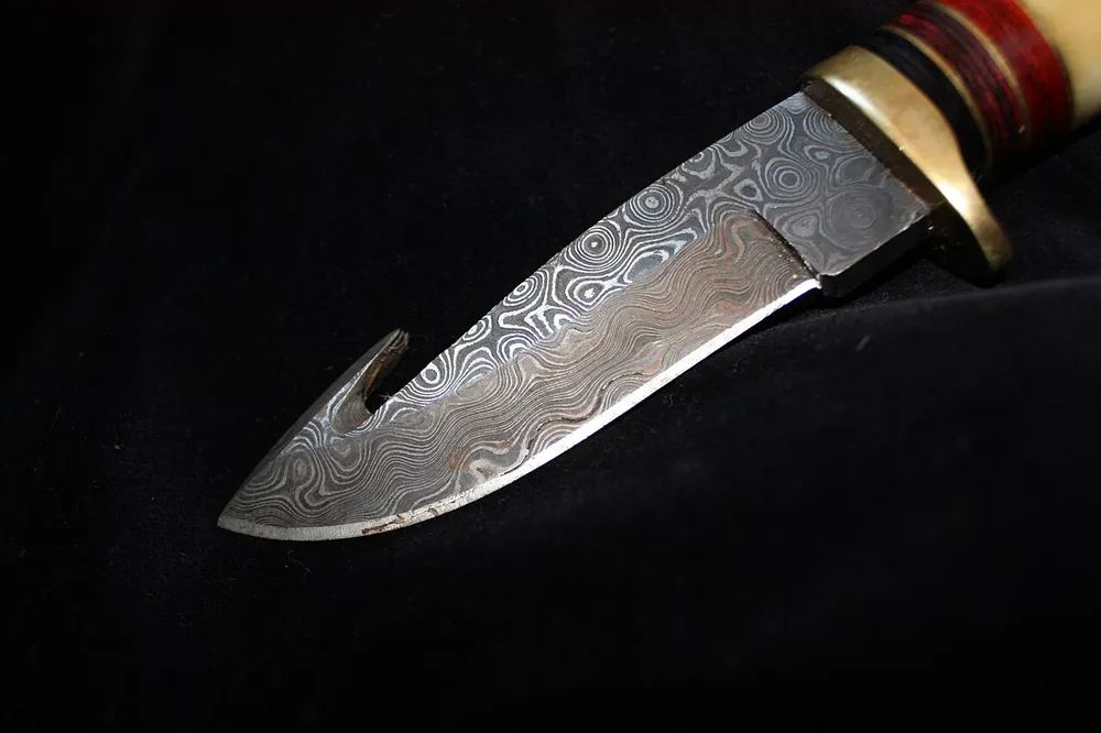 Damascus hunting knife with a gut hook, collector-grade like CS2 souvenir items